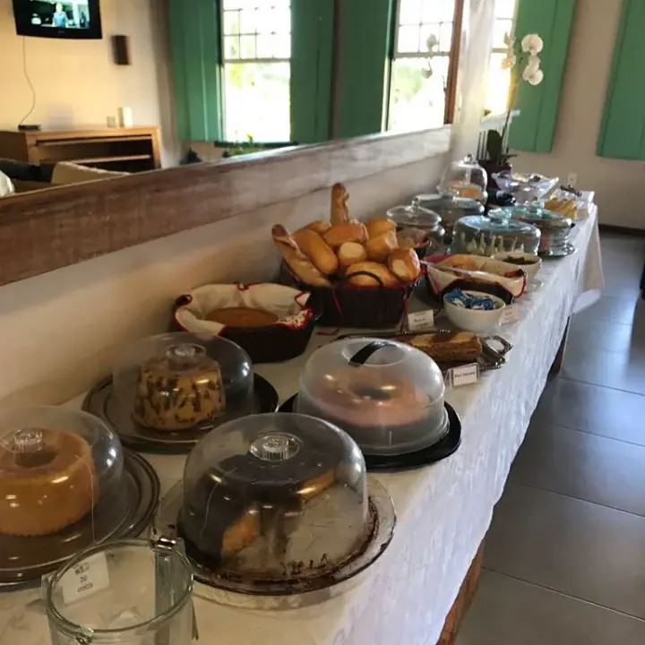 Mesa completa del desayuno, con panes, pasteles, canastas, vajilla y recipientes