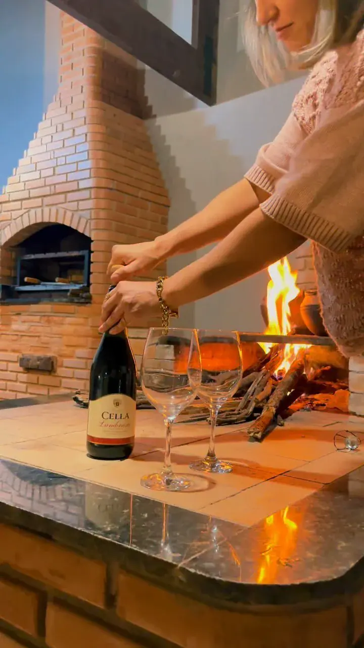 Fuego encendido junto a una pared de ladrillos y una copa de vino