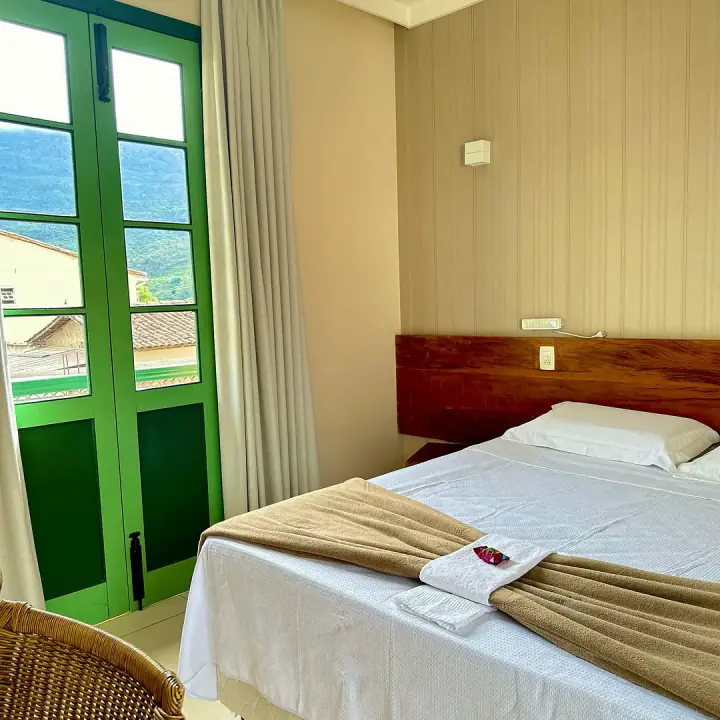 Habitación con cama de madera, puerta verde y vista de la sierra